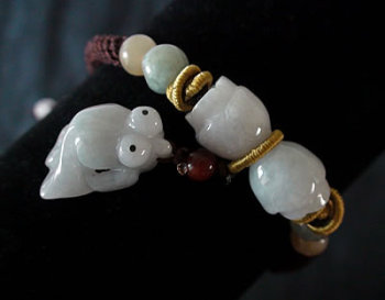 Bracelet en jade. Pi�ces demi-rondes avec petit poisson en pendeloque sur fils tress�s. Jade-France