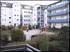 Blick aus dem Wohnzimmer mit Balkon in den Innenbereich der Anlage