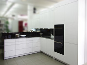 Rotpunkt Designerküche / Musterküche: Grifflose Fronten in Laminat weiß glänzend, Arbeitsplatte Granit braun antique
