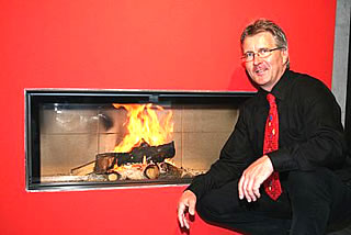 Ernst Knutti vor dem Ofen Attika, ein Highlight in der Ausstellung der Interkamin AG in Unterseen. Foto: Michael Schinnerling