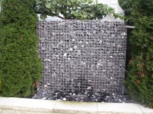 Gabione zwischen Hecke